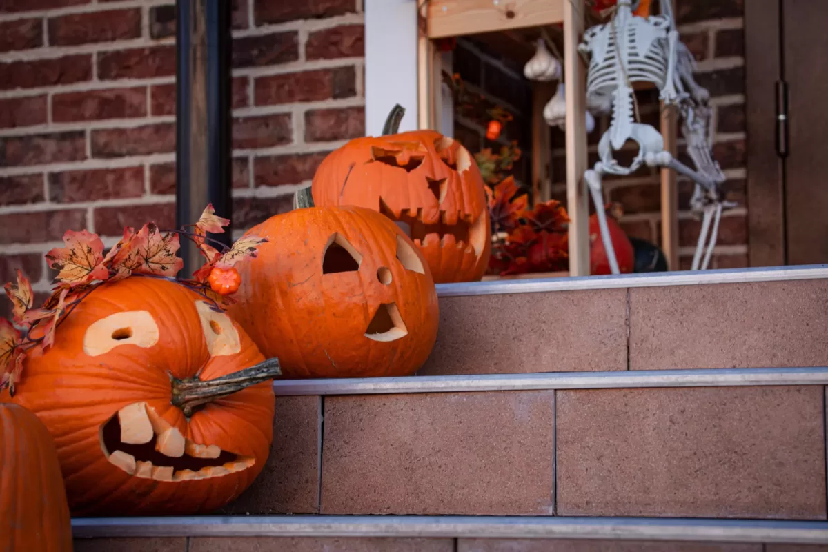 three carved pumpkins in front of a house